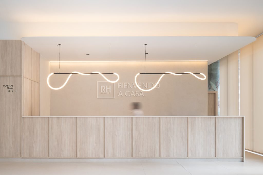 Recepción del Hotel RH Arena Gandía con iluminación neón y mensaje Bienvenido a Casa