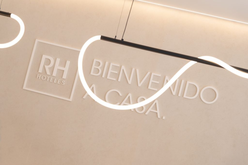 Detalle cartel RH Hoteles Bienvenido a Casa con iluminación neón en recepción Hotel Arena Gandía