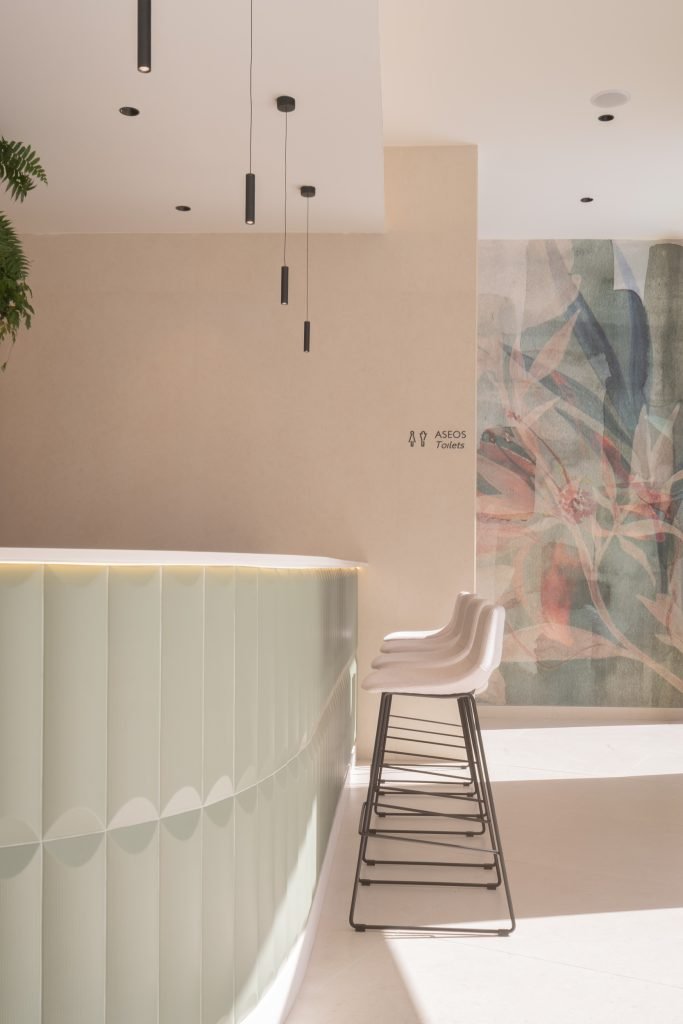 Zona interior con lámparas cilíndricas colgantes, plantas tropicales y mural artístico Hotel RH Arena Gandía