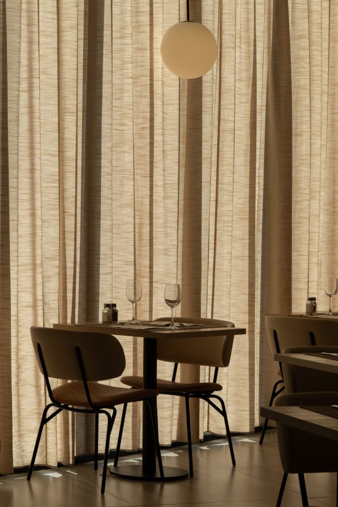 Detalle lámpara esférica colgante y cortinas de lino en restaurante Hotel RH Arena Gandía