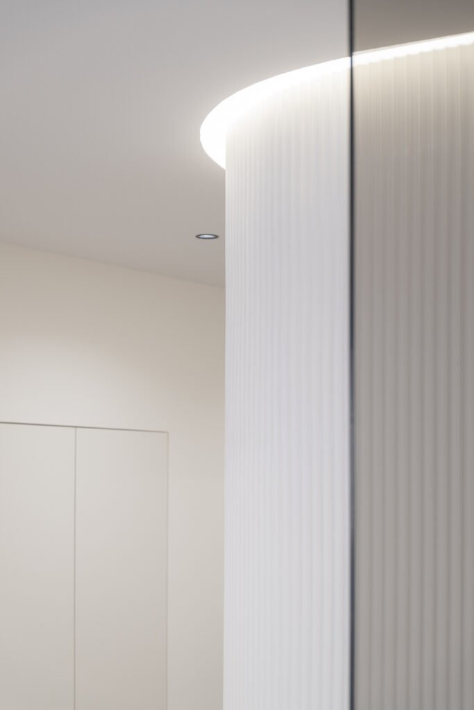Detalle arquitectónico del techo curvo con iluminación LED y panel de lamas verticales en clínica Odentia