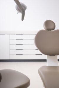 Primer plano del sillón dental beige y la lámpara cenital del gabinete de la clínica Odentia
