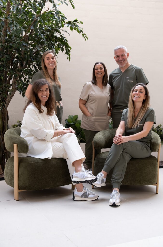 Equipo de profesionales de la clínica dental Odentia posando en la sala de espera con uniformes verdes