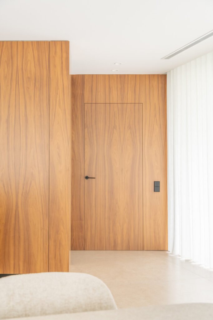 Puerta de madera integrada en el revestimiento del pasillo — Casa en el Mediterráneo, Fran Esbrí Studio, Castellón | Jesús Castelló